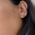 Close-up of a person wearing a green emerald earrings 