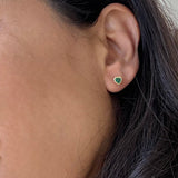 Close-up of a person wearing a green emerald earrings 