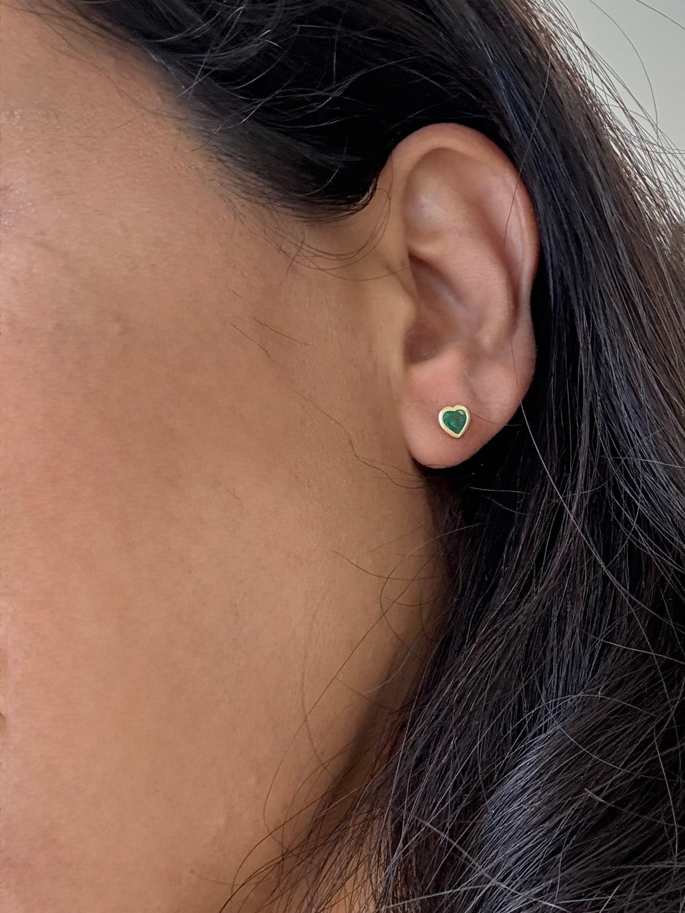 Close-up of a person wearing a green emerald earrings 